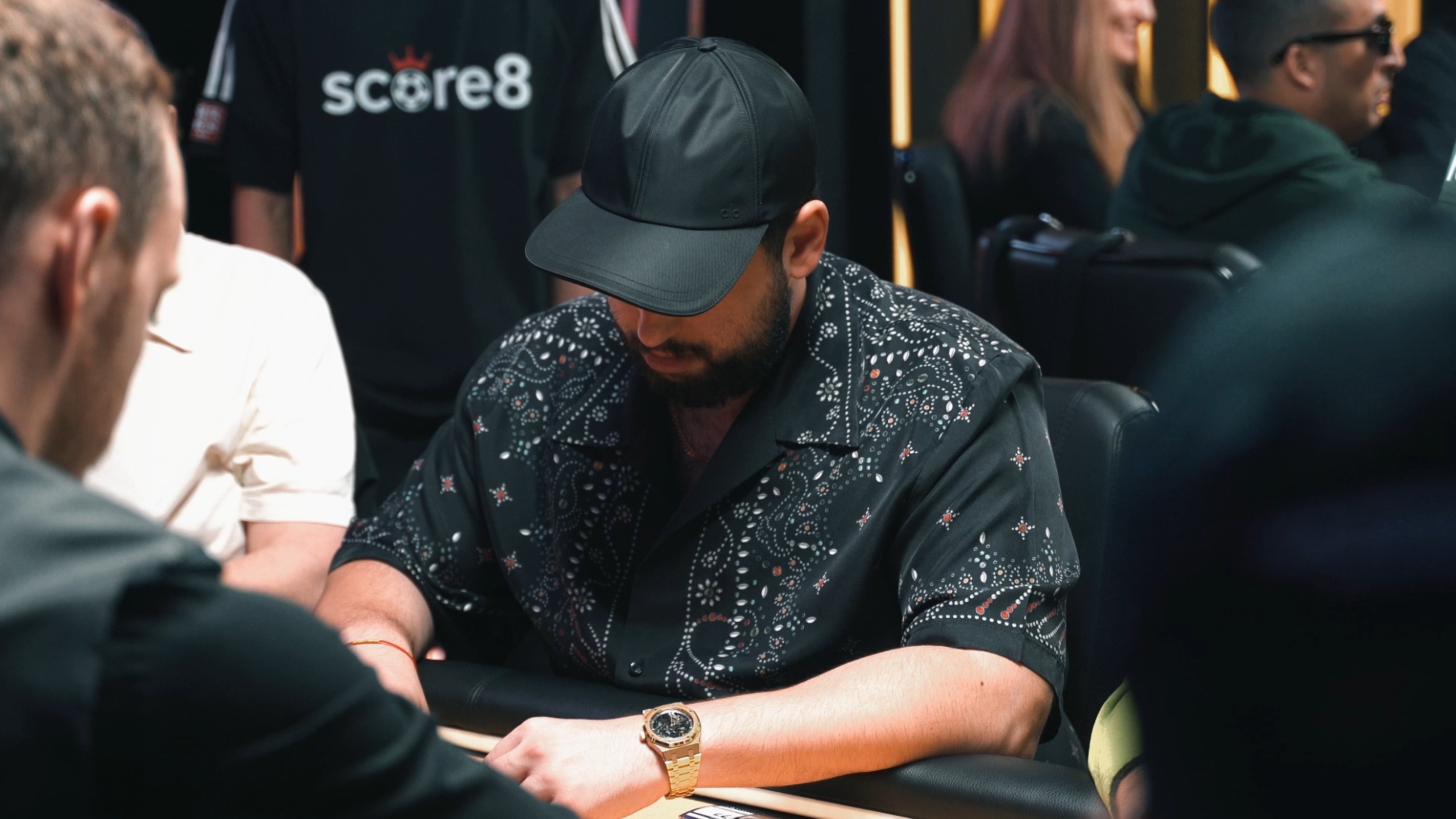Player focused at the Triton Poker table with Score8 team branding behind him